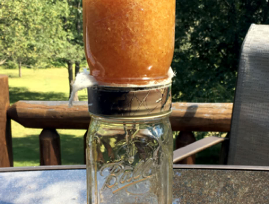 Close-up of a golden honeycomb dripping fresh honey outdoors, showcasing natural hexagon patterns.